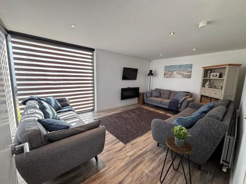 Una sala de estar con dos sofás y un televisor. en Detached Modern Home Portstewart, en Portstewart
