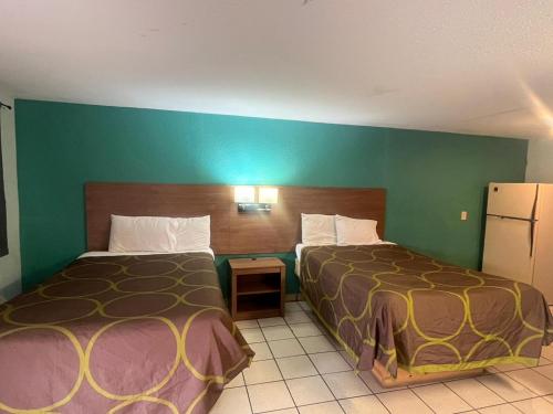 a hotel room with two beds and a green wall at Sun Motel in San Antonio