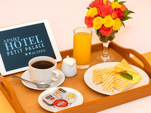 a table with a tray of food and a cup of coffee and flowers at Apart Hotel Petit Palace Suites in Lima