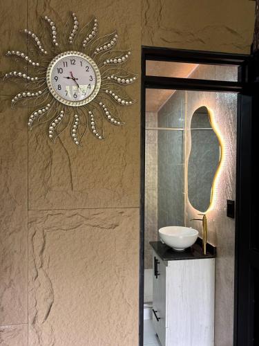 a clock on the wall of a bathroom with a sink at Tesoro Quimbaya IG quimbayacabana in La Florida