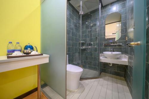 a bathroom with a toilet and a sink and a mirror at QiQiaoWu Fashion Hotel - Beijing Songjiazhuang Subway Station in Beijing