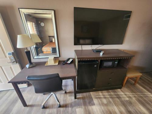 a desk with a mirror and a chair in a hotel room at Satellite Inn in Alamogordo