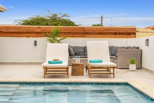 two chairs and a table next to a swimming pool at New Villa Jaburibari in Paradera