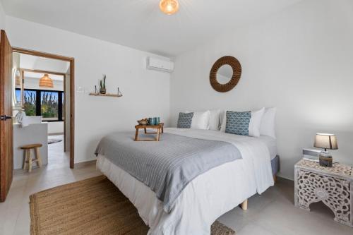 a white bedroom with a large bed and a mirror at New Villa Jaburibari in Paradera