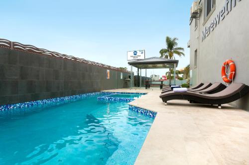 a swimming pool with chairs next to a building at Merewether Motel in Newcastle