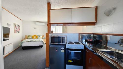 a kitchen with a stove and a sink and a bed at Motel Six in Whangarei