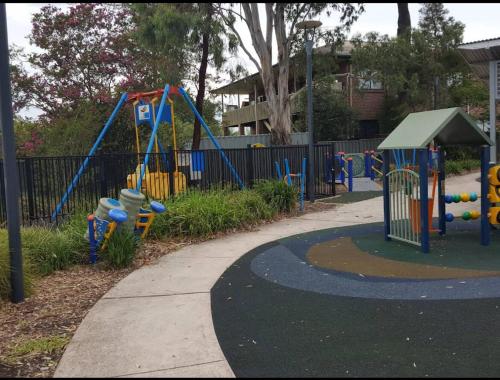 a playground with colorful equipment in a park at Peaceful 2BR Villa Shops & Parks Ingleburn in Ingleburn