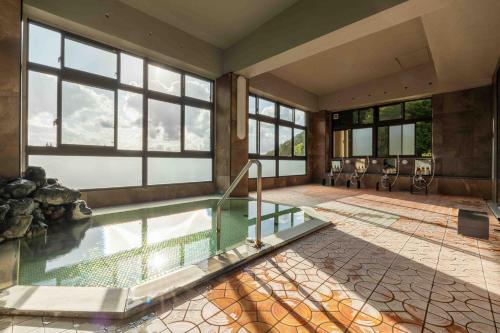 a large room with a swimming pool with windows at Nozawa View Hotel Shimataya in Nozawa Onsen