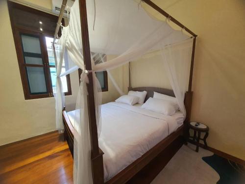 a bedroom with a canopy bed with white sheets at The Courtesan at Yaowarat, townhome 80 Sqm in Samphanthawong