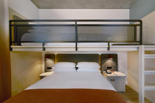 a bedroom with a bunk bed with a white bedspread at Moxy Sydney Airport in Sydney