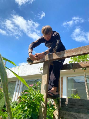 a man is leaning on a wooden fence at Berry homestay 1 in Buon Ma Thuot