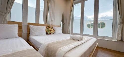 a bedroom with two beds and a large window at Sele House in Ha Tien