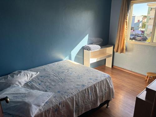 a blue bedroom with a bed and a window at AP familiar com parquinho perto do centro in Pelotas