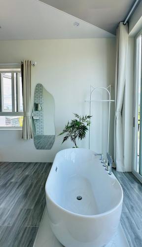 a white bathroom with a large white tub at Sele House in Ha Tien