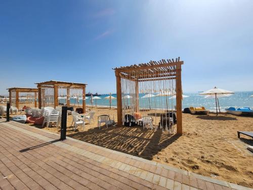 a pavilion on the beach with chairs and an umbrella at Peaceful Challette Two Bedrooms in Murano El Sokhna in Ain Sokhna