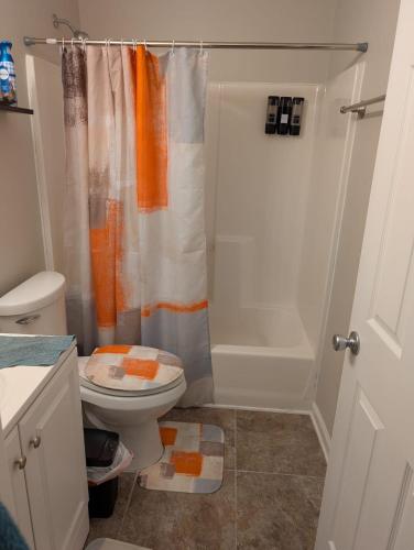 an orange and white bathroom with a toilet and a shower at 2 Bedroom Basement Home in Conley