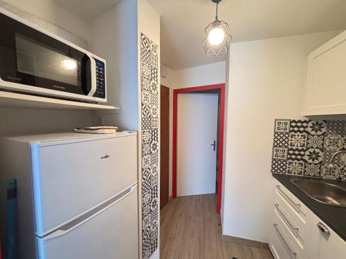 une cuisine avec un réfrigérateur et un micro-ondes dans l'établissement Studio accueillant pour 3, accès direct plage - FR-1-197-621, à Les Sables-dʼOlonne