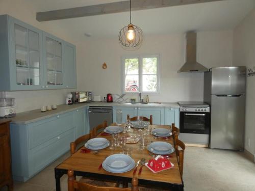 a kitchen with a table with chairs and a refrigerator at Notre Dame de Monts (85) - Maison de vacances 82 m² environ - 6 personnes - FR-1-540-323 in Notre-Dame-de-Monts