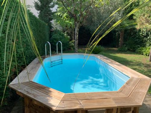 une piscine dans une cour arrière avec une terrasse en bois et une piscine bleue dans l'établissement Arcachon: Villa Basque 4 Chambres, Plage & Commerces à 300m - FR-1-420-160, à Arcachon