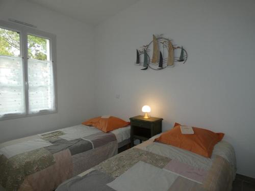 two beds in a room with a window and a lamp at Notre Dame de Monts (85) - Maison de vacances 82 m² environ - 6 personnes - FR-1-540-323 in Notre-Dame-de-Monts