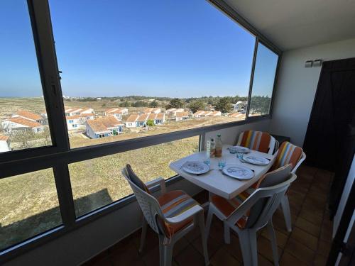 une table et des chaises dans une pièce avec une grande fenêtre dans l'établissement Appartement moderne 3 pièces, vue mer, parking privé, 5 couchages - FR-1-224C-348, à Saint-Hilaire-de-Riez