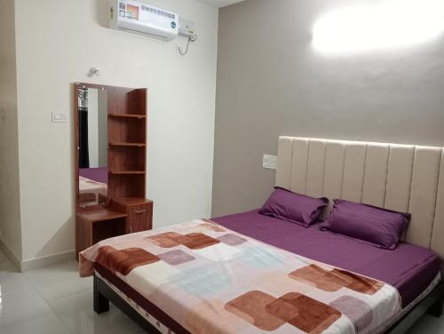 a bedroom with a bed with purple pillows and a mirror at hope villa homestay gokarna in Gokarna