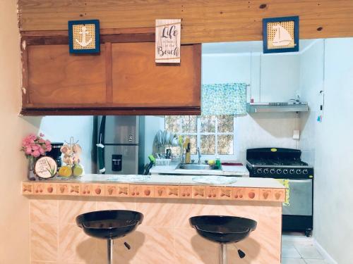 a kitchen with two black stools at a counter at La casa del almendro in Concepción de La Vega