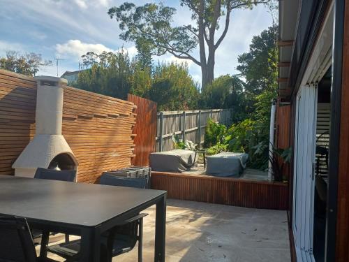 a patio with a table and a fireplace at Romanic Garden View 1 bed Apartment with ocean views at Stanwell Tops in Stanwell Park