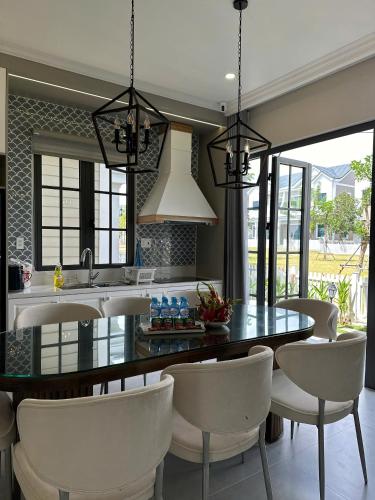 a kitchen with a dining table and white chairs at Biệt thự nghỉ dưỡng NovaWorld in Bình Sum