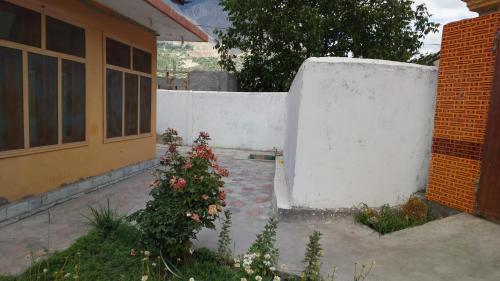 a white fence next to a house with flowers at Cherry blossom guest house in Sumaiyar