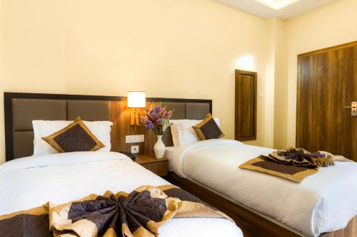 two beds in a hotel room with flowers on them at Indrakeel in Gangtok