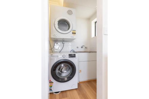 a laundry room with a washing machine and a washer at Sandpebbles 1 Pebbly Beach in Forster