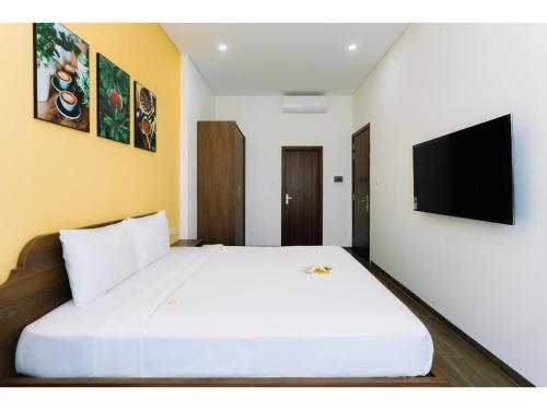 a bedroom with a large white bed with a flat screen tv at Fivitel Nam Hoi An Riverside in Thuận An