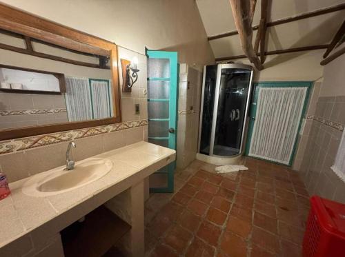 a bathroom with a sink and a shower with a mirror at Hermosa casa de campo in Tinquipaya