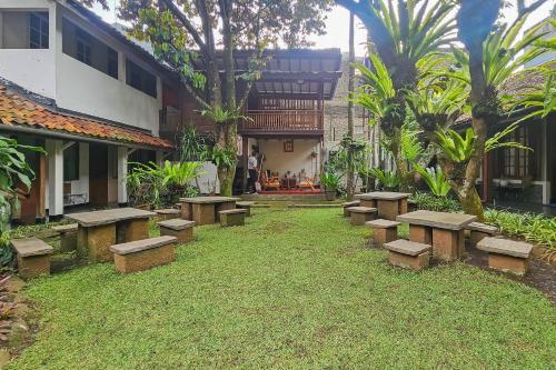 a row of benches in a yard next to a building at Urbanview Rumah Ebo Dago Bandung in Bandung
