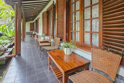 a porch with wooden tables and chairs and windows at Urbanview Rumah Ebo Dago Bandung in Bandung