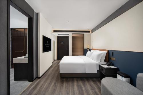 a hotel room with a white bed and a bathroom at Mehao Lizhi Hotel Kashgar Donghu Park Branch in Kashgar