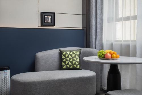 a chair and a table with a bowl of fruit on it at Mehao Lizhi Hotel Kashgar Donghu Park Branch in Kashgar