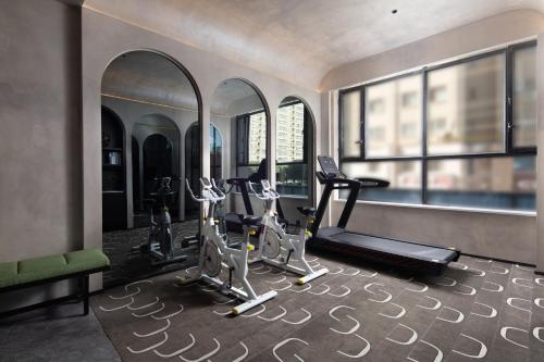 a gym with treadmills and ellipticals in a room with windows at Mehao Lizhi Hotel Kashgar Donghu Park Branch in Kashgar
