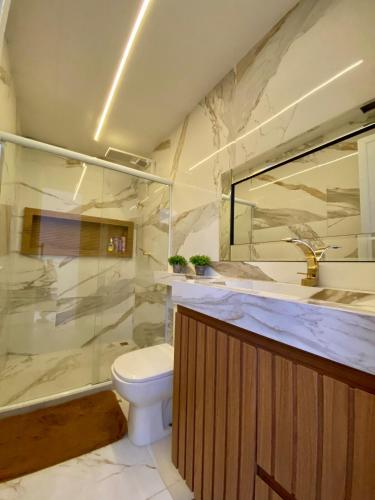 a bathroom with a toilet and a glass shower at Casa de praia, mangaratiba sahy in Mangaratiba
