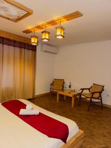 a bedroom with a bed and two chairs and a table at Kesar Palace Hotel & Restaurant, Skardu in Skardu