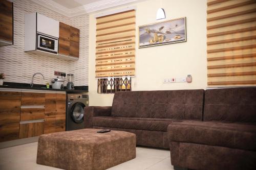a living room with a brown couch and a kitchen at New Stylish 1 Bedroom Adjiringanor in Ashalebotwe