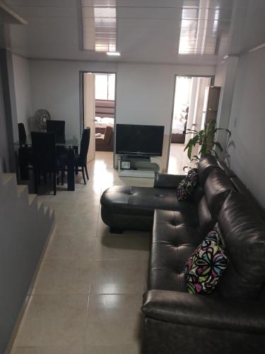 a living room with a leather couch and a television at Apartamento en el Centro de Pereira in Pereira