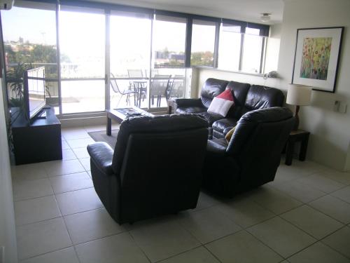 a living room with a black leather couch and chairs at Fairthorpe Apartments in Brisbane