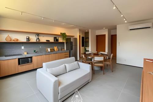 a living room with a white couch and a kitchen at Villa Naluri - Seu Refúgio a 50 metros da praia em Japaratinga in Japaratinga