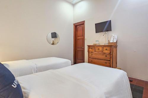 a bedroom with two beds and a dresser with a tv at Urbanview Rumah Ebo Dago Bandung in Bandung