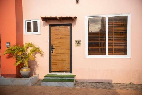 a pink house with a wooden door and a plant at Executive 2 Bedroom RealShala East Legon Hills in Maijaw