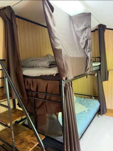 a bunk bed in a room with curtains and a mattress at 旅人宿ゆるっと in Iburi