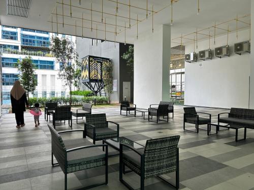 Gua SaiにあるAlinea Suites Shah Alam by Rumah Mamaのテーブルと椅子、女性と子供がいるロビー