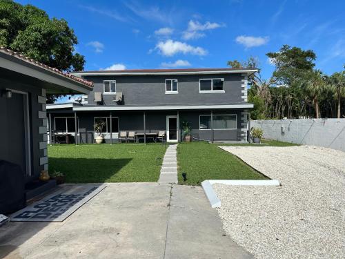 a gray house with a lawn in front of it at Exec Suites Men only 7 min to Ocean in Pompano Beach